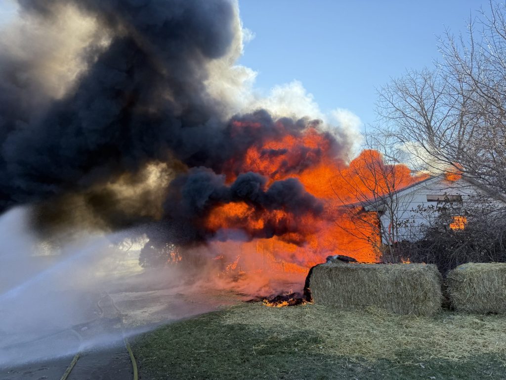 Hose stream on a house fire with heavy black smoke during an acquired structure burn