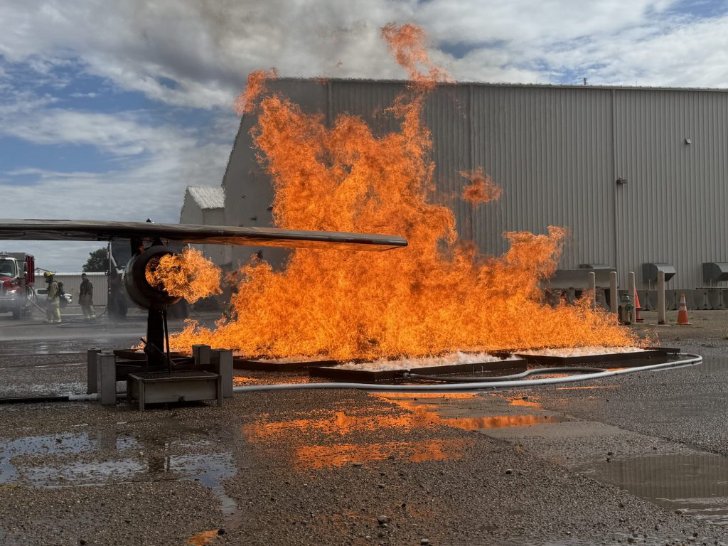 Aircraft wing fire prop with pan fire beside a hangar