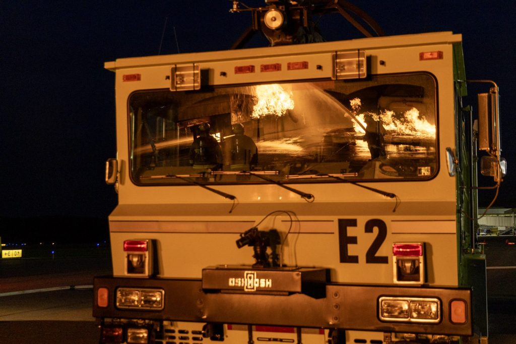 ARFF crash truck at night with fire reflected in the windshield