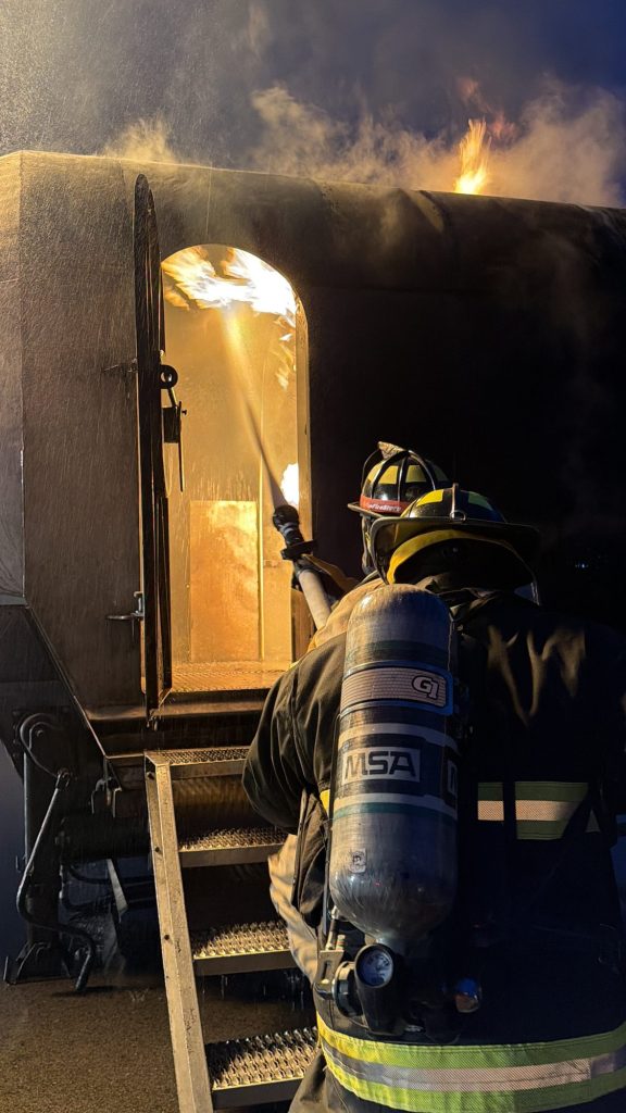 Firefighter on air entering an aircraft door with fire inside