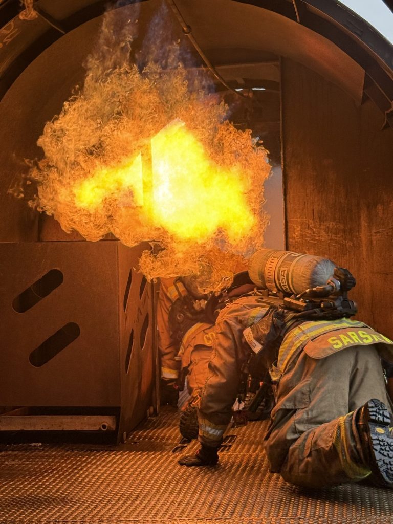 Firefighters staying low under a fireball in a flashover trainer