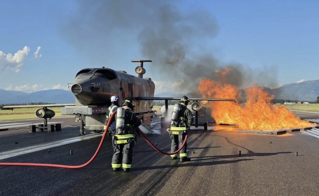 Two hose teams attacking a fuel spill fire at an aircraft trainer