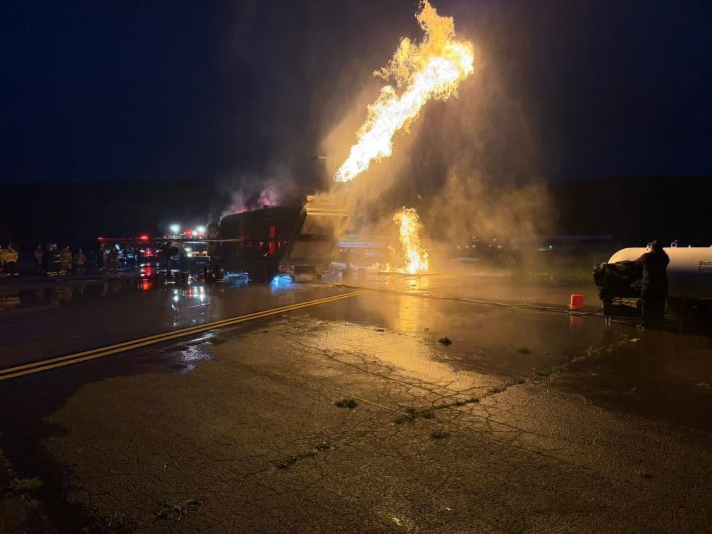 Engine fire and running fuel fire on a mobile aircraft fire trainer at night with crews standing by