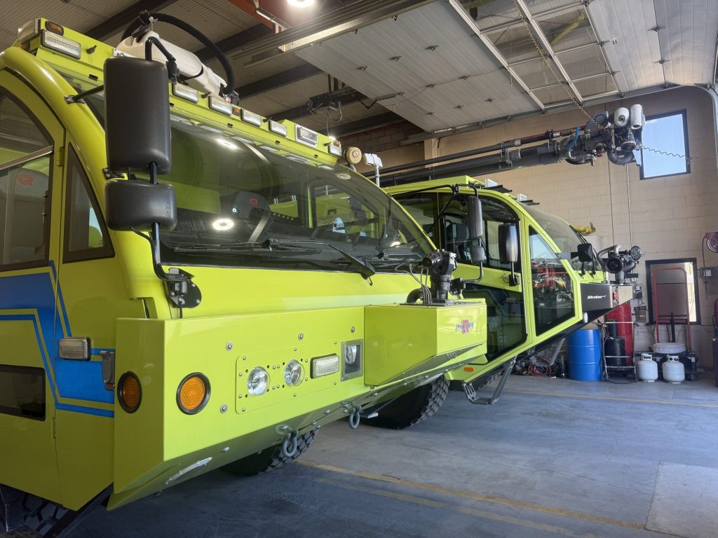 Two ARFF crash trucks parked in a fire station bay