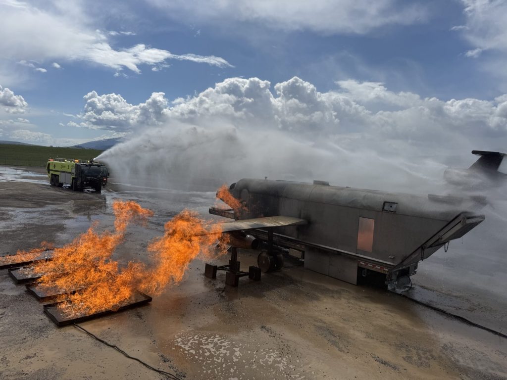 ARFF crash truck roof turret flowing over a wing and fuel spill fire on the aircraft trainer