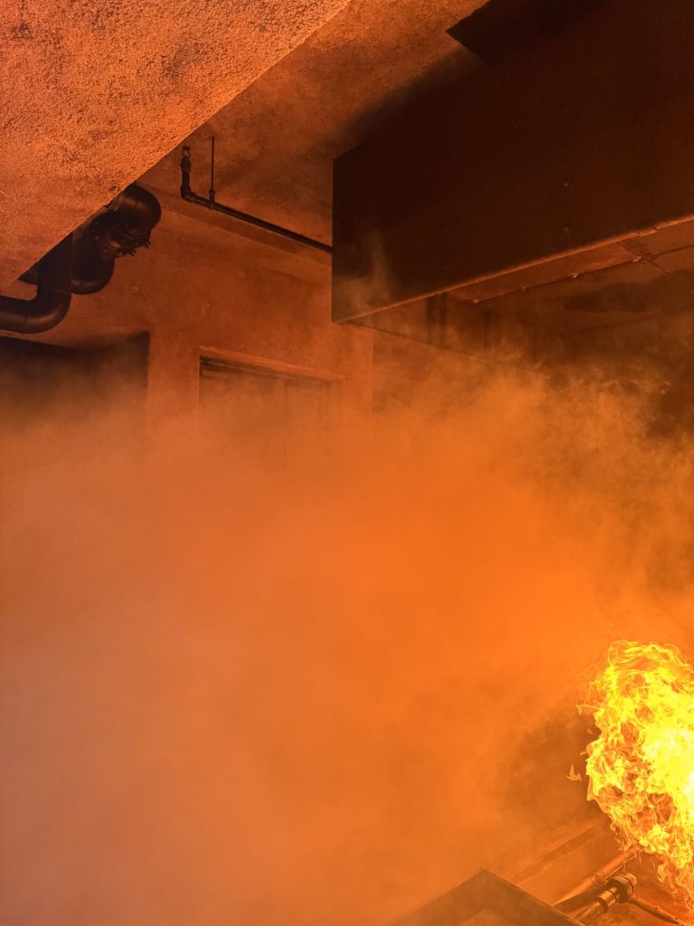 Flames and heavy orange smoke inside a fire trainer