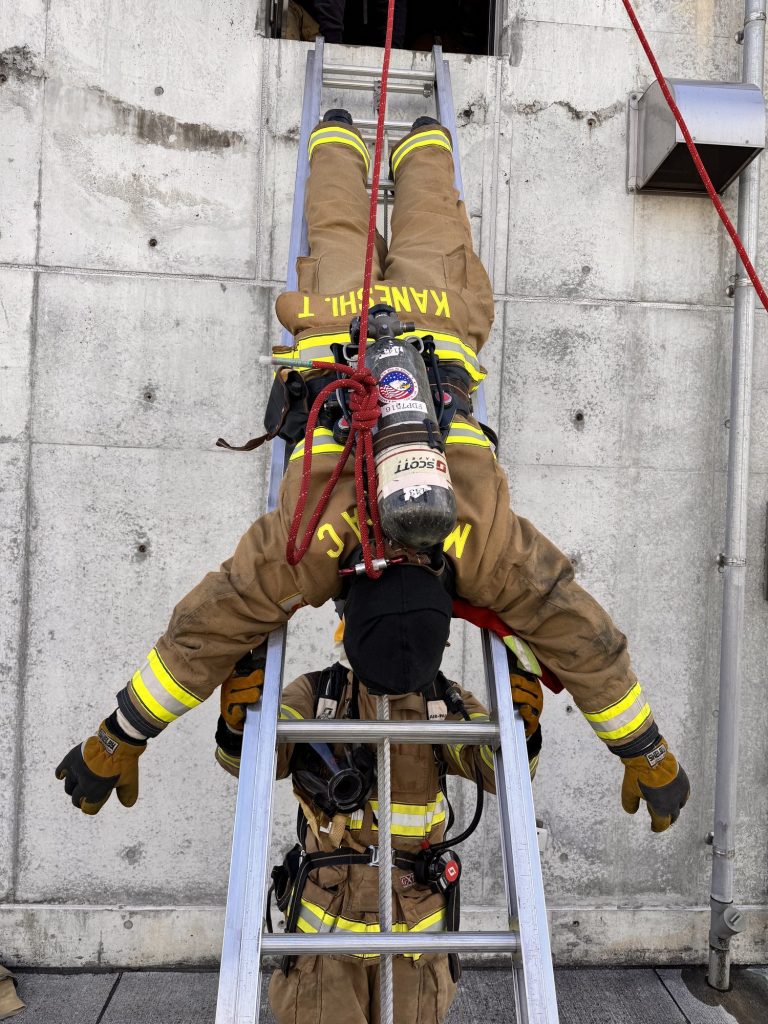 Firefighter coming head-first down a ladder in a bailout drill