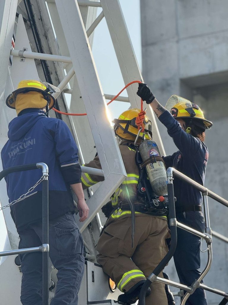 Firefighters climbing a training tower ladder with SCBA