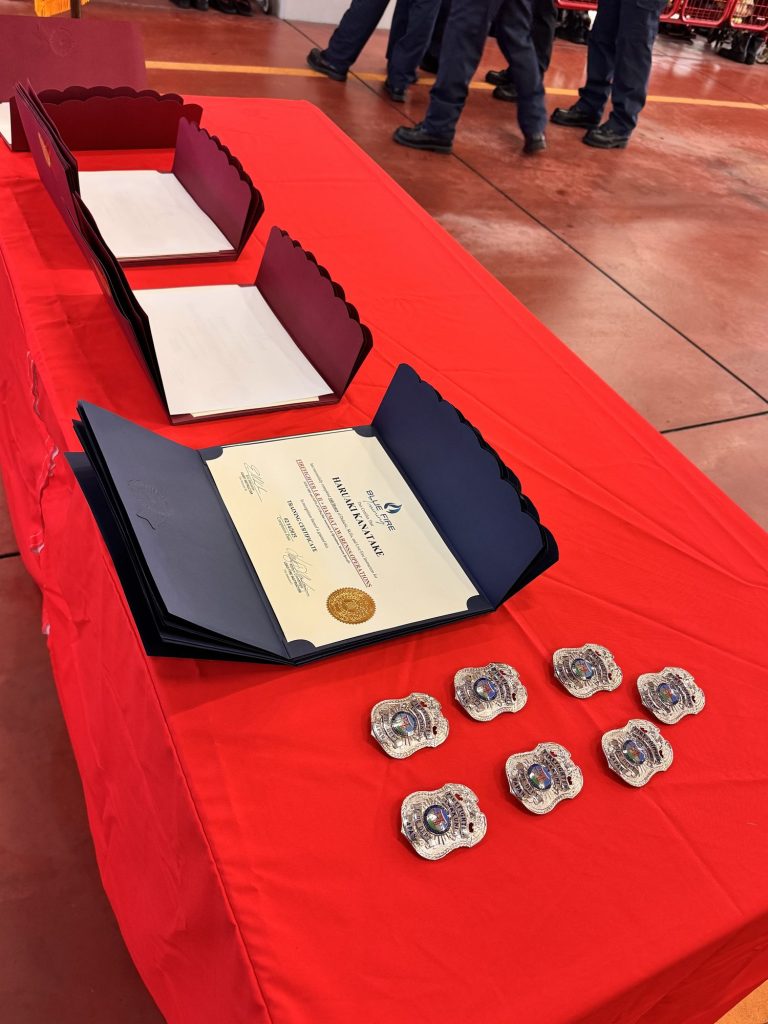 Graduation certificates and challenge coins laid out on a red table