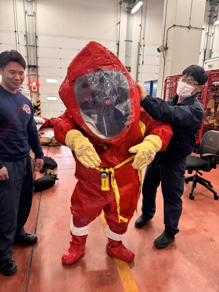 Firefighter being helped into a red Level A hazmat suit