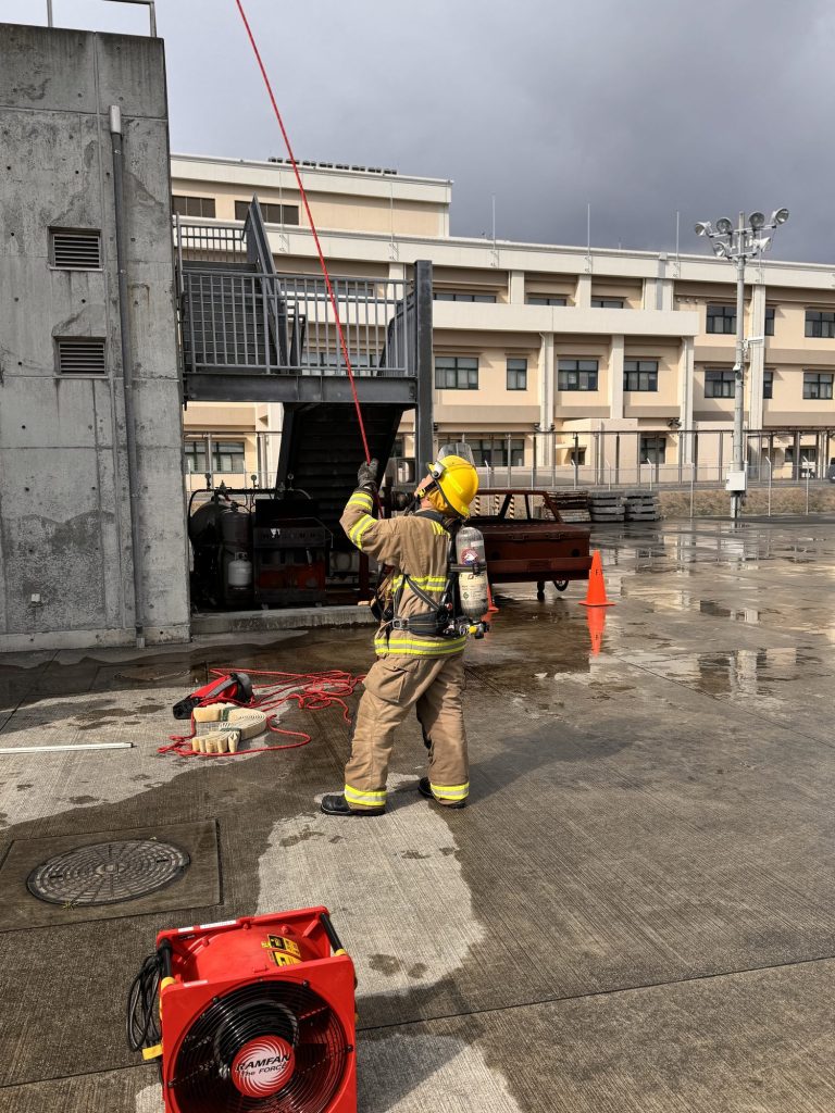 Firefighter working a rope system at the base of a training tower